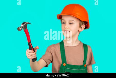 Petit garçon portant un casque, constructeur en hardhats marteau. Casque de construction pour enfants, casque de sécurité. Martelage par marteau. Petit constructeur en casque et hummer. Enfant Banque D'Images