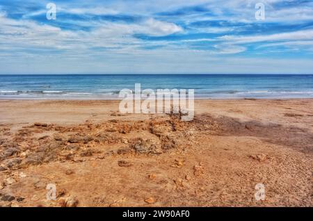 Les gens nagent dans l'eau calme le long d'un littoral vide Banque D'Images