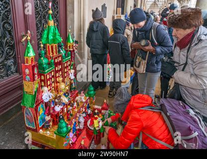 Artiste met la touche finale à sa Szopka (scène de la Nativité de Noël) exposée à l'ouverture du concours annuel en décembre, événement inclus dans la liste du patrimoine culturel de l'UNESCO, aux arcades de Sukiennice (salle des vêtements), place principale du marché, Kraków, Pologne Banque D'Images