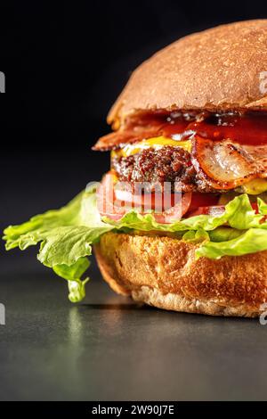 Délicieux hamburger boeuf et bacon, sandwich, restauration rapide, nourriture délicieuse, gros plan sur fond noir. Banque D'Images