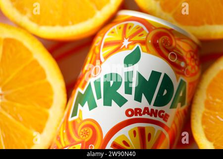 KIEV, UKRAINE - 7 JUILLET 2023 Mirinda boisson orange avec de nombreuses oranges fraîches sur fond coloré Banque D'Images