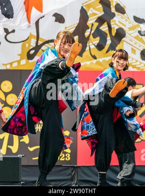 Deux jeunes danseuses japonaises Yosakoi dansent sur scène et donnent un coup de pied aux jambes en montrant leurs chaussures jika tabi lors d'un festival à Kumamoto. Banque D'Images