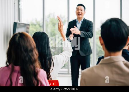 Lors d'une conférence, une foule diversifiée d'hommes d'affaires lève la main pour poser des questions, voter ou Banque D'Images