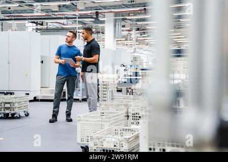 Deux collègues avec tablette numérique parlant dans une usine Banque D'Images
