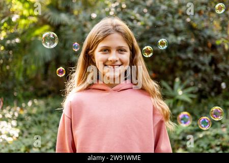 Heureuse fille blonde avec des bulles dans le parc Banque D'Images