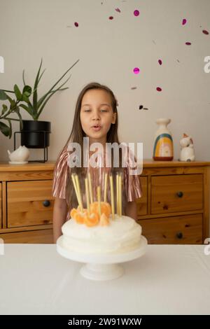 Fille heureuse soufflant des bougies sur le gâteau d'anniversaire à la maison Banque D'Images