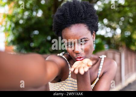 Jeune femme soufflant baiser et prenant selfie Banque D'Images