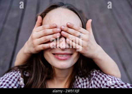 Mains de fils couvrant les yeux de la mère Banque D'Images