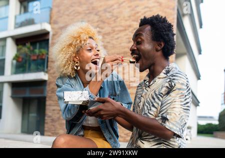 Heureuse femme transgenre nourrissant des sushis à son petit ami Banque D'Images