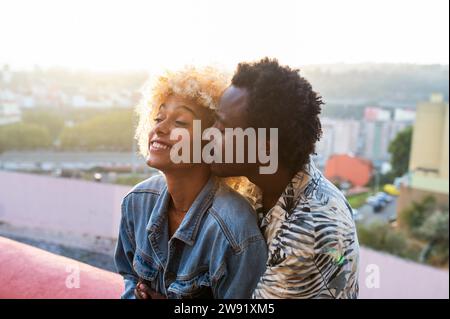 Petit ami romantique embrassant une femme transgenre au coucher du soleil Banque D'Images