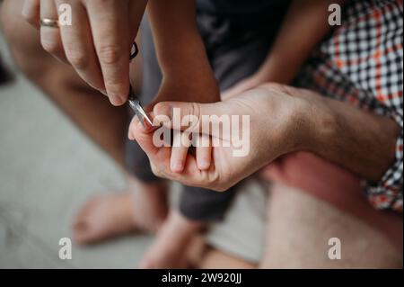 Père coupant les ongles de son fils à la maison Banque D'Images