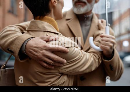 Couple amoureux s'embrassant debout sous un parapluie Banque D'Images