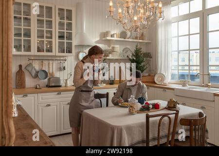 Homme décorant des biscuits avec femme debout à table dans la cuisine Banque D'Images