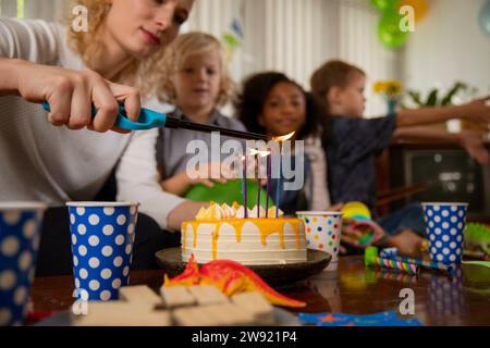 Femme allumant des bougies sur le gâteau d'anniversaire à la maison Banque D'Images