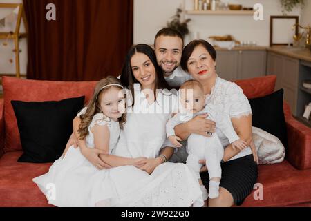 Famille souriante assise sur un canapé dans la salle de séjour à la maison Banque D'Images