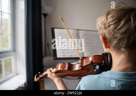 Garçon pratiquant le violon avec partition à la maison Banque D'Images