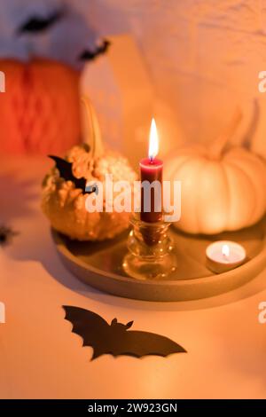 Citrouilles avec bougies et chauve-souris artificielle sur la table Banque D'Images