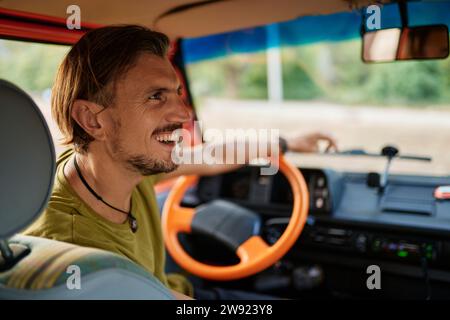 Heureux homme mûr assis sur le siège du conducteur à l'intérieur du camping-car Banque D'Images