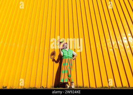 Heureuse femme âgée tenant le jouet Pinwheel devant le mur jaune Banque D'Images