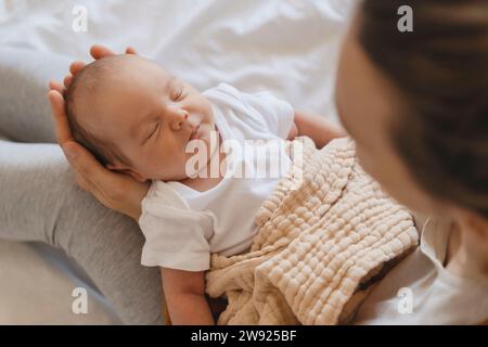 Mignon bébé nouveau-né dormant dans les bras de la mère à la maison Banque D'Images