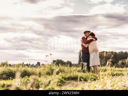 Amoureux couple senior serrant dans le champ par jour ensoleillé Banque D'Images