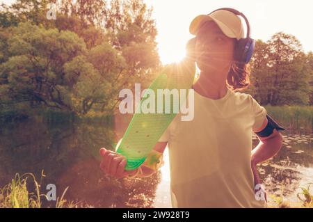 Portrait d'une adolescente avec un skateboard. Concept de style de vie sportif. Supports mixtes Banque D'Images