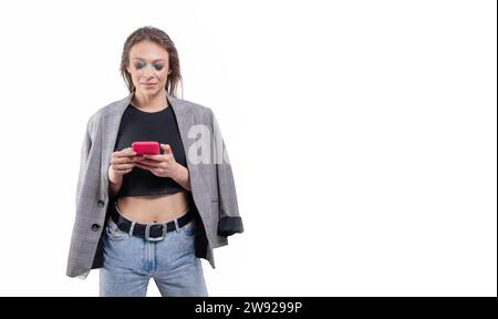 Portrait d'une belle fille dans une veste avec un téléphone portable à la main. Fond blanc. Supports mixtes Banque D'Images