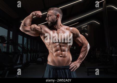 Homme musclé posant dans la salle de gym. Concept de fitness. Supports mixtes Banque D'Images