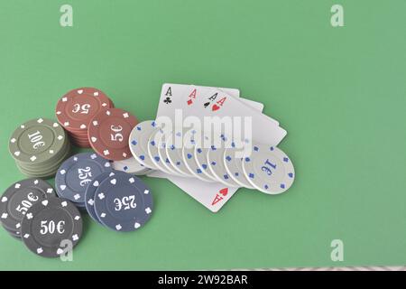 Jetons de casino et quatre as affichés sur une table verte, suggérant un jeu de poker, des cartes de poker et des jetons Banque D'Images