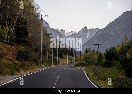 Route dans la vallée de l'Ala Archa, sommets glaciaires en arrière-plan au coucher du soleil, parc national d'Ala Archa, montagnes de Khirgiz Ala-Too, région de Chuy Banque D'Images