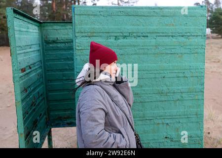 Portrait de femme portant des vêtements d'automne, parlant au téléphone dans Vintage Beach Changing Booth Banque D'Images