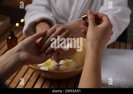 Femme recevant un traitement de la main à la table en bois dans le spa, closeup Banque D'Images