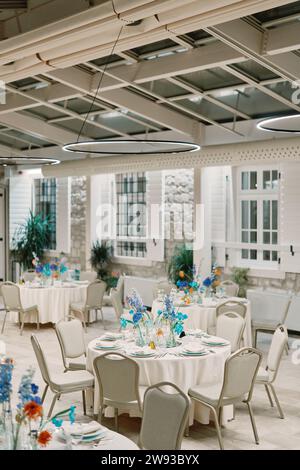 Des fleurs dans des vases se dressent sur des tables posées dans un restaurant Banque D'Images