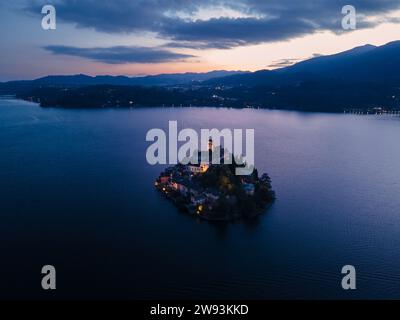 Île de San Giulio dans le lac d'Orta dans le Piémont, Italie. vue aérienne du drone à l'heure bleue du coucher du soleil. lumières de la ville et ciel coloré Banque D'Images