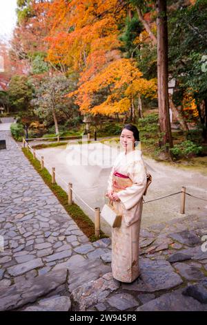 Kyoto, Japon. Femme portant un kimono dans le jardin de feuillage Honen-in Temple Fall. Les érables deviennent rouges en automne. Escalier en pierre de construction traditionnel japonais Banque D'Images