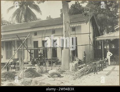 Maison à Steigers, 1914 - 1919 photographie Une maison en construction en échafaudage, avec différents ouvriers au travail, à droite l'architecte Riphagen. Probablement à Medan. Photo dans l'album photo du cabinet d'architectes néerlandais Bennink et de la société d'entrepreneurs Riphagen à Medan dans les années autour de 1914-1919. Alors que le support photographique gélatine argentique impression tandis que Banque D'Images