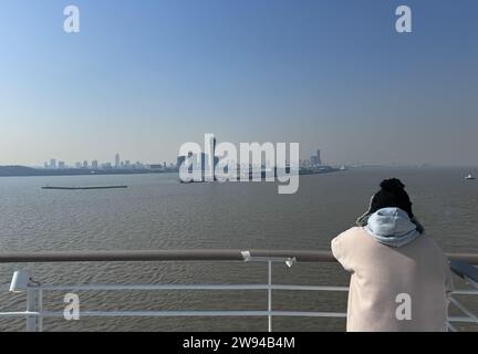 (231224) -- SHANGHAI, 24 déc. 2023 (Xinhua) -- Un passager à bord du navire de croisière 'Adora Magic City' regarde en arrière alors que le navire part du terminal de croisière international de Shanghai Wusongkou à Shanghai, dans l'est de la Chine, le 24 décembre 2023. Le premier grand navire de croisière de construction nationale de Chine, le «Adora Magic City», a quitté un port de Shanghai dimanche, commençant son opération d'essai. Transportant des invités et près de 1 300 membres d'équipage du monde entier, le navire est parti après midi dimanche du terminal de croisière international de Shanghai Wusongkou et devrait revenir au terminal Banque D'Images