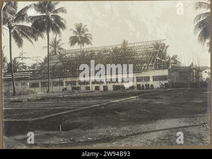 Locaux commerciaux en construction, 1914 - 1919 photo vue d'un grand local commercial en construction, dans le site de construction de friches au premier plan, palmiers gauche et droit, probablement à Medan. Photo dans l'album photo du cabinet d'architectes néerlandais Bennink et de la société d'entrepreneurs Riphagen à Medan dans les années autour de 1914-1919. Alors que le support photographique gélatine argentique impression tandis que Banque D'Images