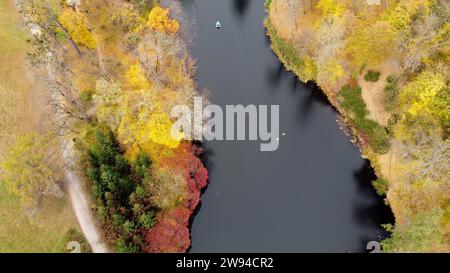 Vue sur le parc d'automne avec des lacs avec des cygnes, des arbres avec des feuilles vert jaune rouge, prairie, architecture, cascade et les gens marchant le long des chemins de terre le jour de l'automne. Arrière-plan naturel. Aménagement paysager Banque D'Images