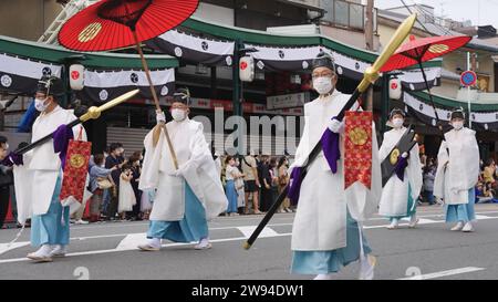 Aperçu du festival Aoi Matsuri à Kyoto au Japon présentant un homme orné d'une tenue traditionnelle tenant gracieusement un parapluie rouge vibrant Banque D'Images