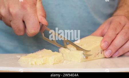 Bloc de fromage bloc de fromage entier transformé avec finesse, comme un chef qualifié manipule un couteau à fromage. Chaque coupe précise dévoile son art culinaire. Banque D'Images