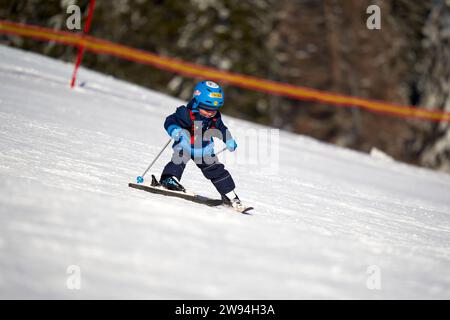 Feldberg, Allemagne - 08 février 2023 : débutant en ski pratiquant le ski alpin sur la neige. Petit garçon apprenant les sports d'hiver à l'école de ski. Parcours de ski Banque D'Images