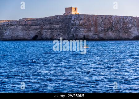 Bateau de pêche en face de la tour Santa Marija Comino, Malte Banque D'Images