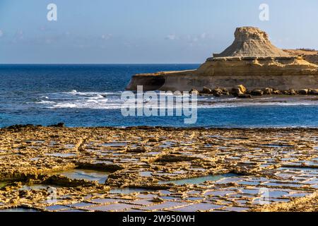 Marais salants de la famille Cini dans la baie de Xwejni, en arrière-plan la White Hill, une formation rocheuse bizarre de grès calcaire. La famille exploite les marais salants dans le nord de Gozo depuis 1860. Magasin de sel Leli Tal-Melh à Xwejni près de Marsalforn, Gozo, Malte Banque D'Images