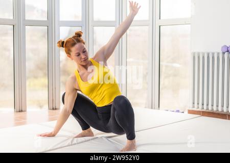 Jeune femme en forme s'étirant dans la salle de gym tout en accroupissant Banque D'Images