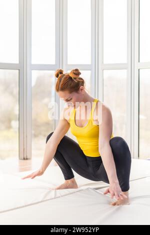 Jeune femme en forme s'étirant dans la salle de gym tout en accroupissant Banque D'Images