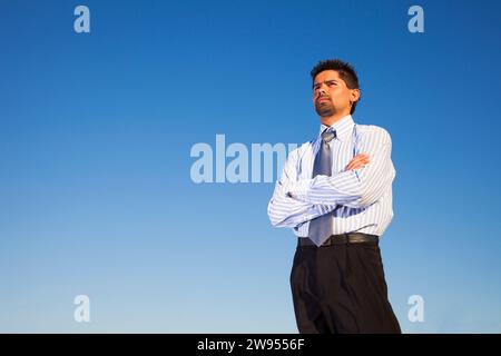 homme d'affaires debout contre le ciel bleu Banque D'Images