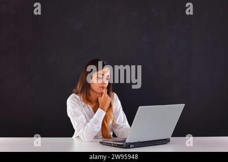 Femme pensant à côté d'un tableau noir Banque D'Images