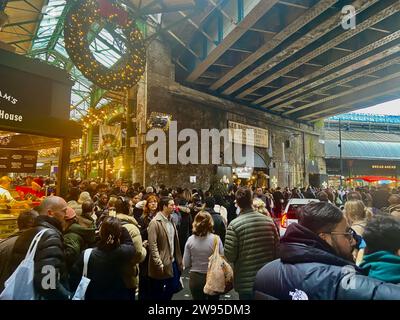 Non exclusif : les acheteurs poussent à travers un Borough Market très occupé la veille de Noël pour acheter des aliments de dernière minute. Banque D'Images