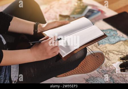 Une femme assise sur une carte et se préparant pour un voyage avec des accessoires de voyage Banque D'Images